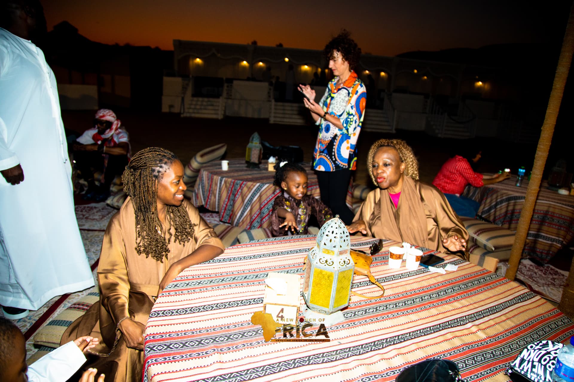ANTOA guests sharing conversation at sunset during the red-dune desert night